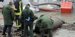 Modige teknikere ser nærmere på bomben, der blev fundet, da der var lavvande i Rhinen.