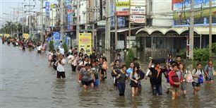 Folk forlader deres arbejdsplads i Thailand efter flodvand brød gennem barrierer i udkanten af Bangkok.