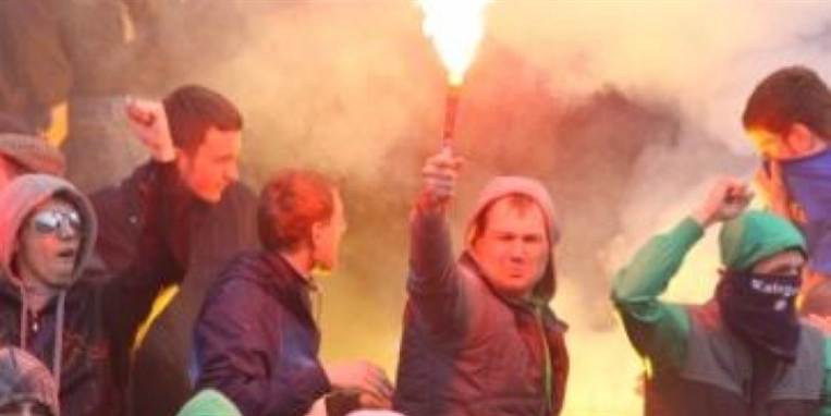 Kvinden har blandt andet kastet flasker og møtrikker efter betjente. På billedet ses en gruppe ukrainske hooligans, der ligeson kvinden er begejstrede for romerlys.