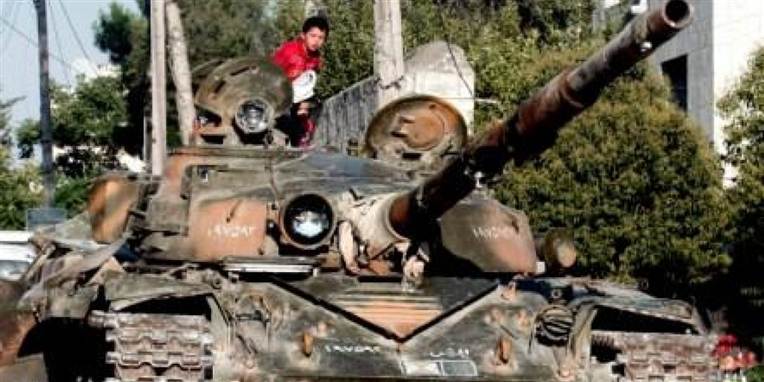 En dreng sidder på en tank ca 30 kilometer udenfor Syriens største by Aleppo, hvor et stort slag er lige om hjørnet.