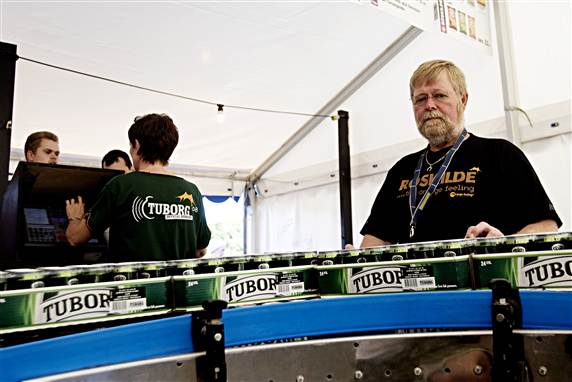 Uffe har selv opfundet transportbåndet, der ved hjælp af jernruller kører kasserne med dåseøl direkte ind i ølboden.