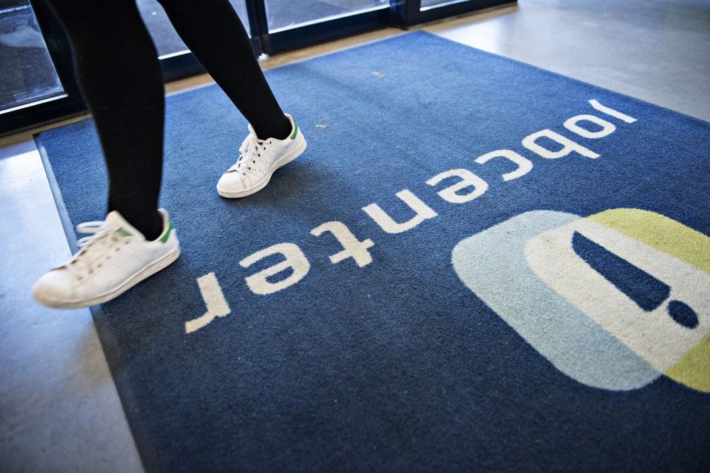 En person går på et gulvtæppe med jobcenter-logo