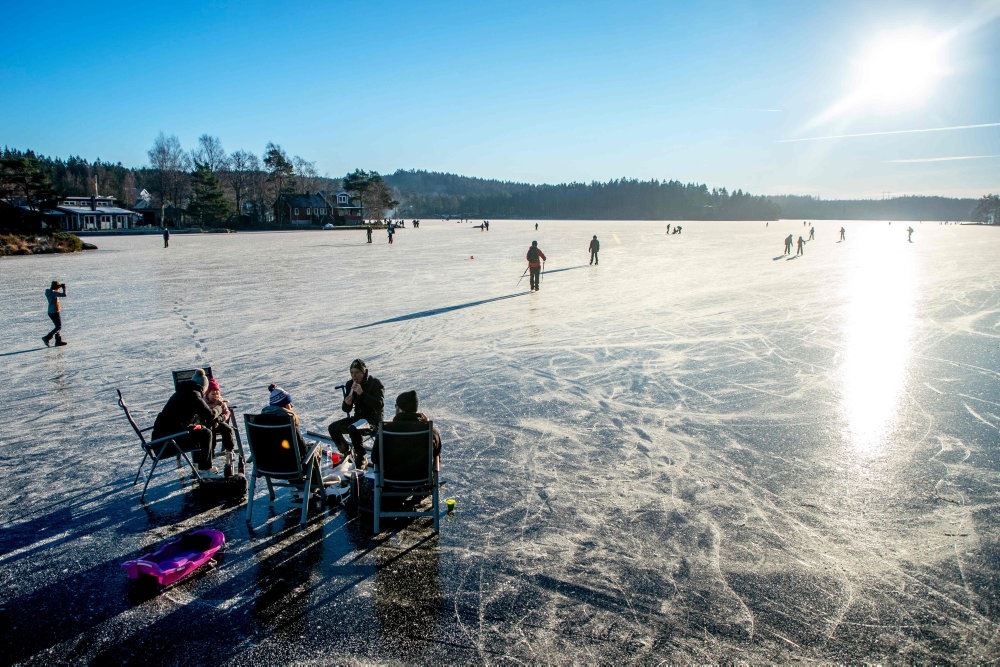 Folk på isen på en svensk sø i solskin