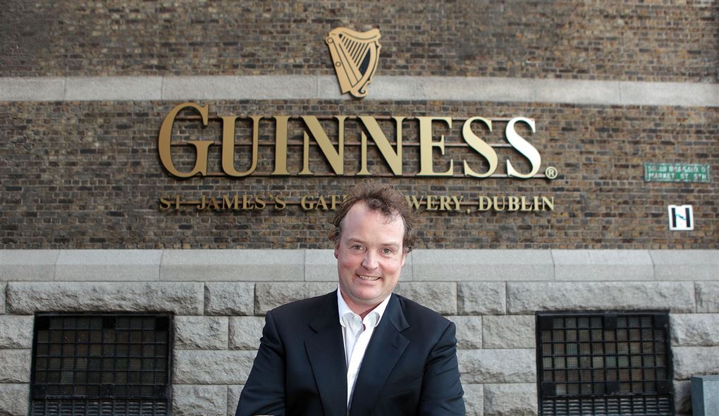 En smilende mand foran Guinness-skilt
