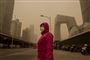 person i rødt tøj står i beijing under sandstorm