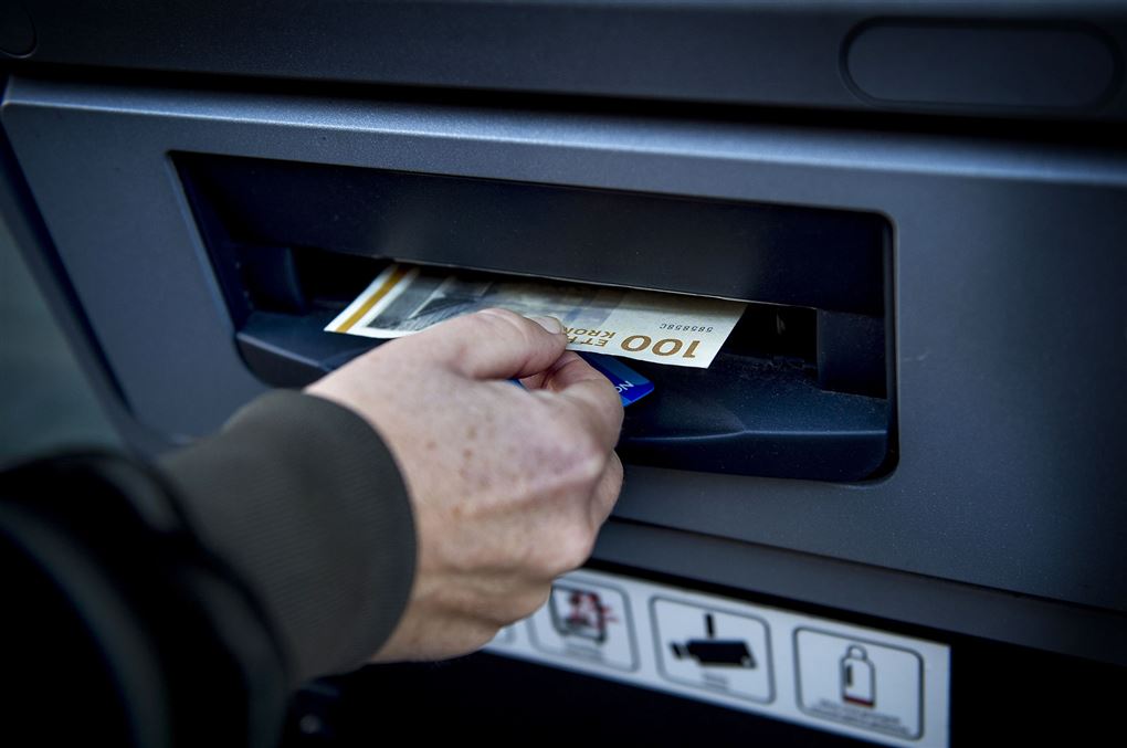 En mand hiver hundrede kroner ud af en pengeautomat. 
