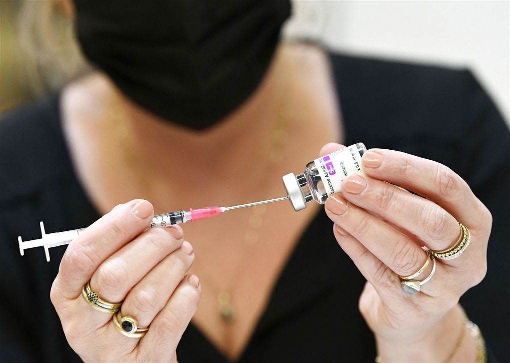 kvinde står med kanyle og vaccineglas