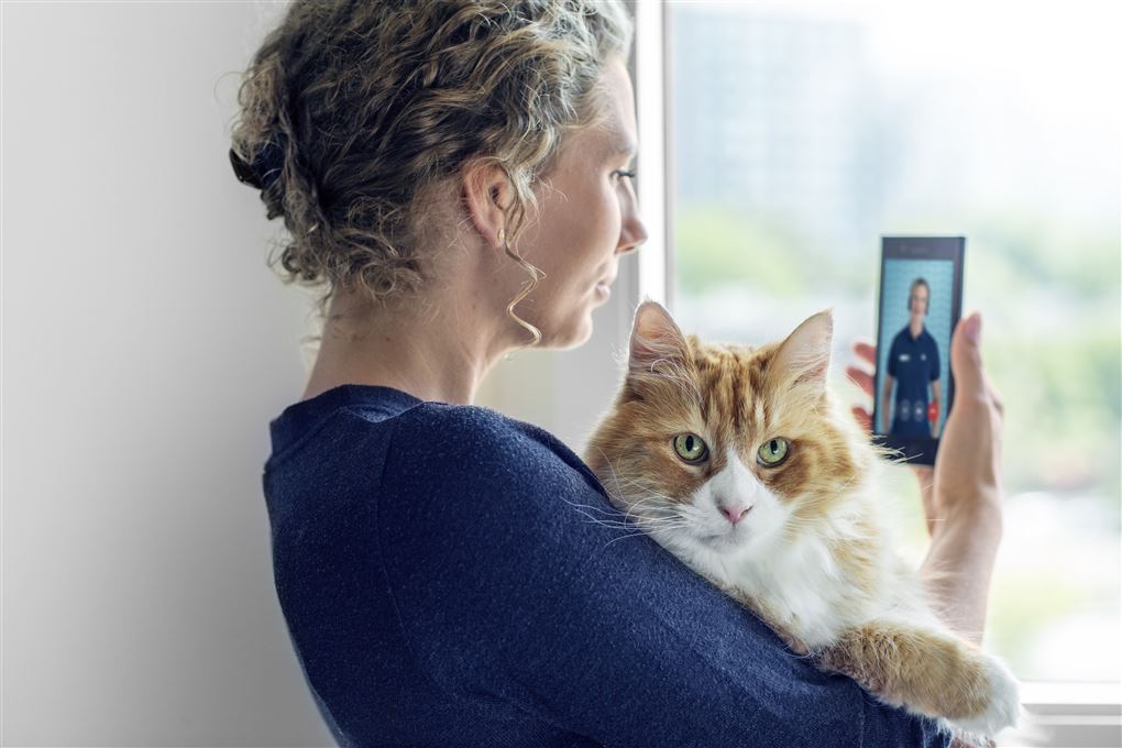 Kvinde med kat på armen og mobil i hånden