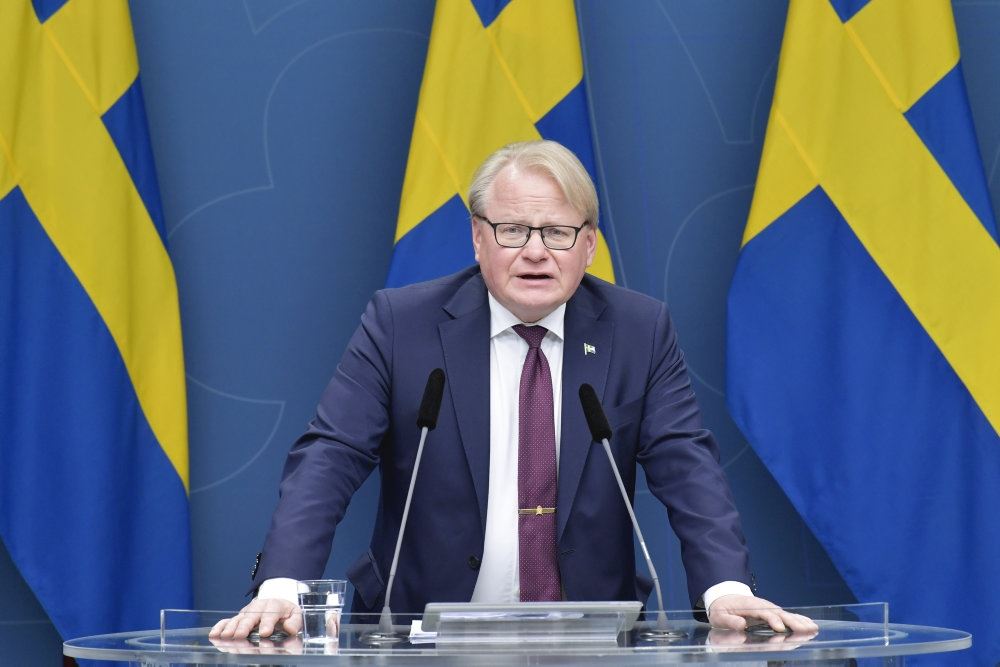 En mand holder tale foran det svenske flag