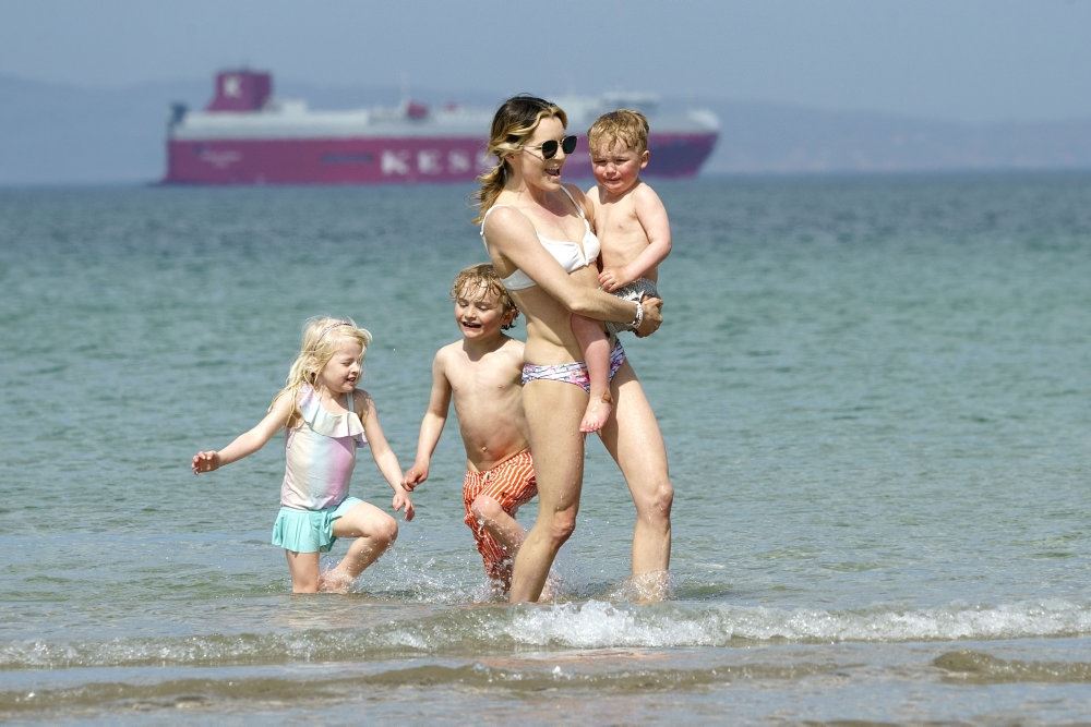 kvinde med tre børn går i vandkanten
