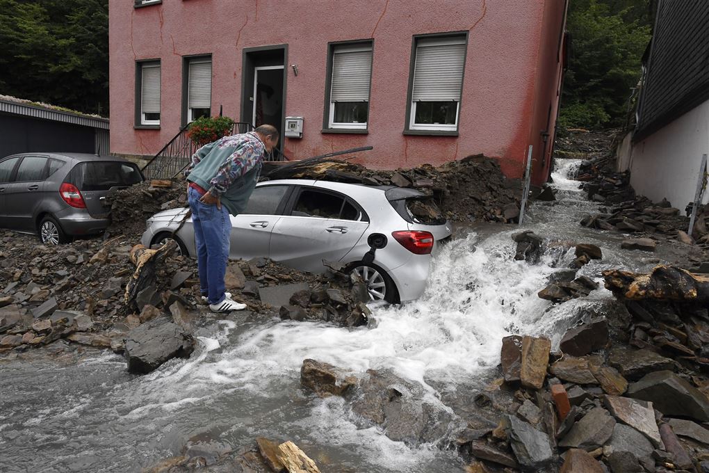 Mand ved bil i oversvømmet gade