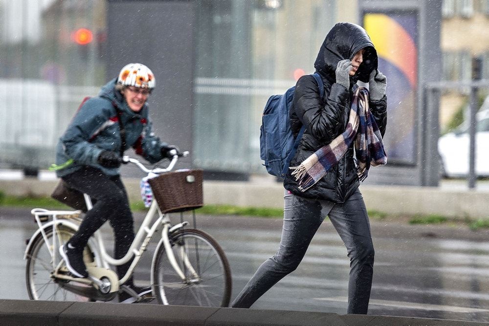 En cyklist og en fodgænger strider sig gennem blæs og regn