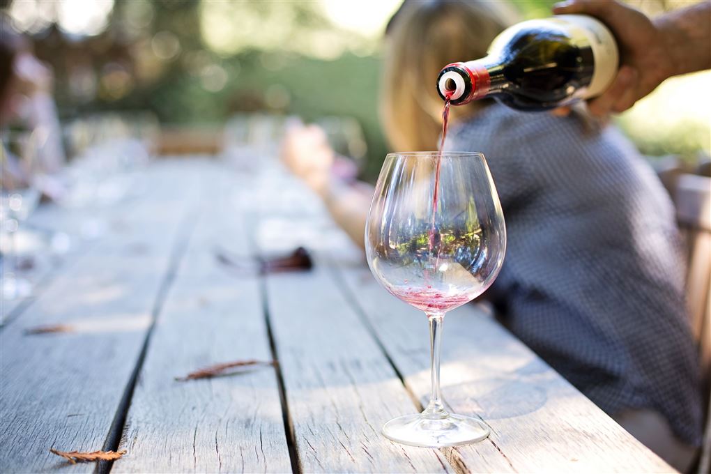 En rødvin bliver hældt op i et glas udenfor