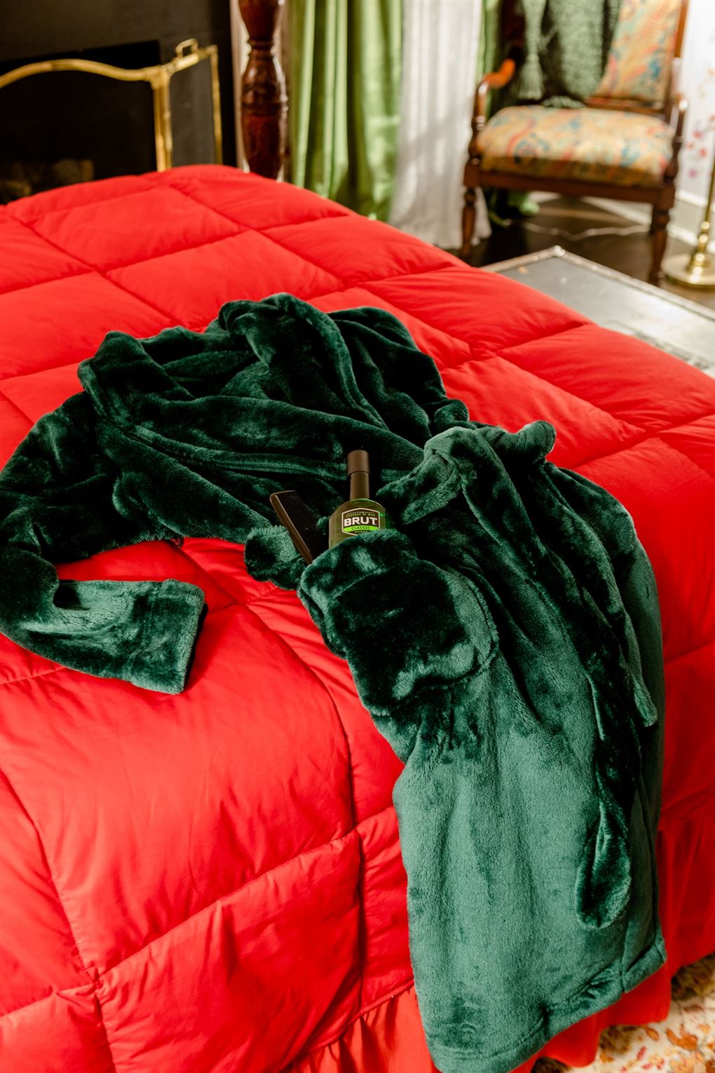 En blød grøn badekåbe ligger på en seng med rødt sengetaæppe. 