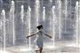 En pige med mundbind løber gennen springvand i Beijing i Kina