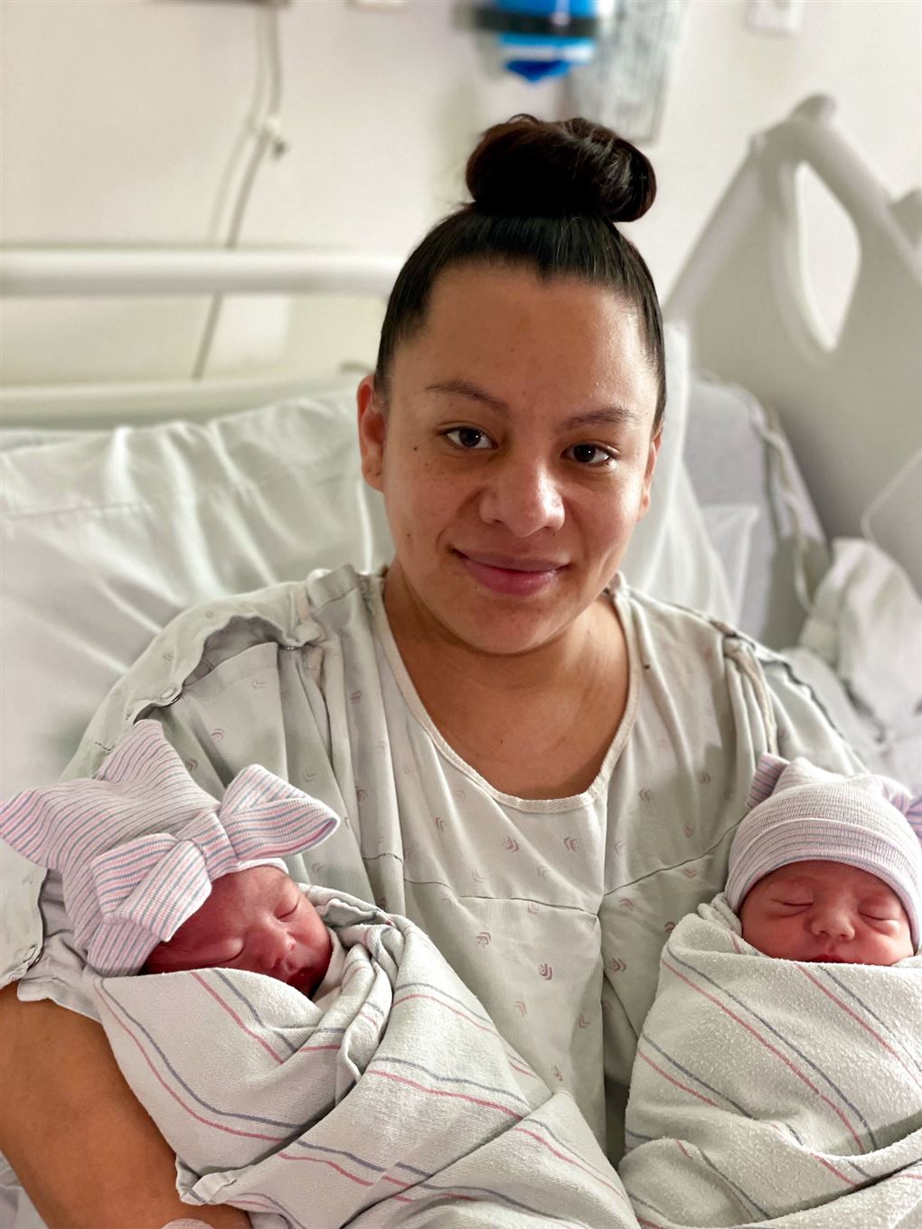 kvinde sidder i hospitalsseng med tvillinger 