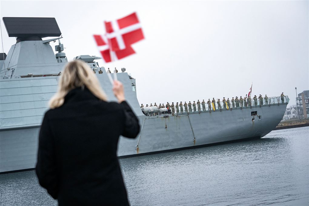 kvinde med flag med fregat i baggrunden 