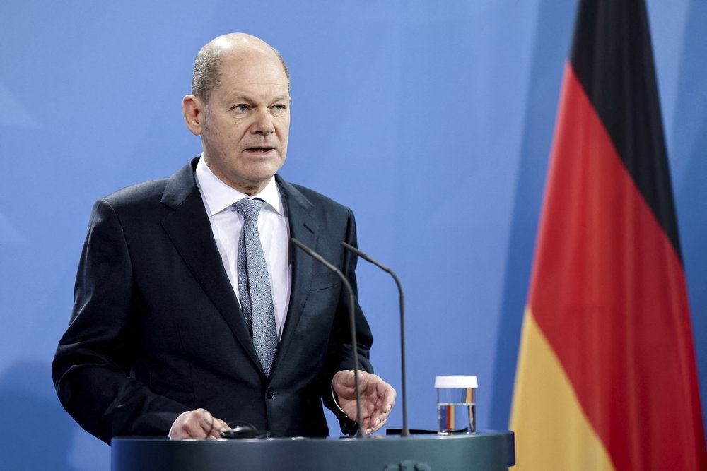 en mand på en talerstol med et tysk flag i baggrunden