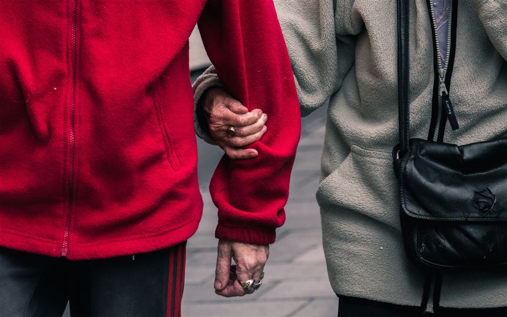 Et aldrende par på gåtur hun holder i hans arm.
