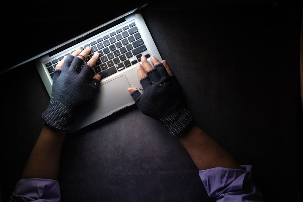 mand med handsker sidder ved computer 