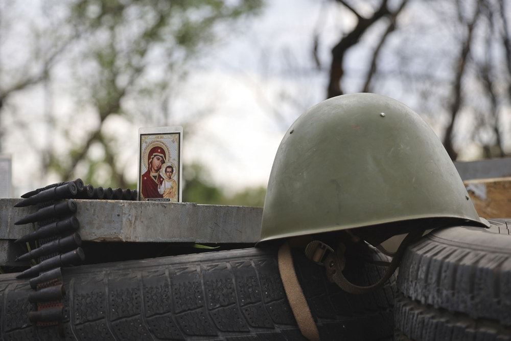Et billede står ved siden af en militærhjelm ved et kontrolpunkt i Mariupol, der er belejret af russiske styrker.
