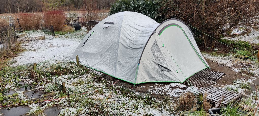 Et telt i en have i snevejr.