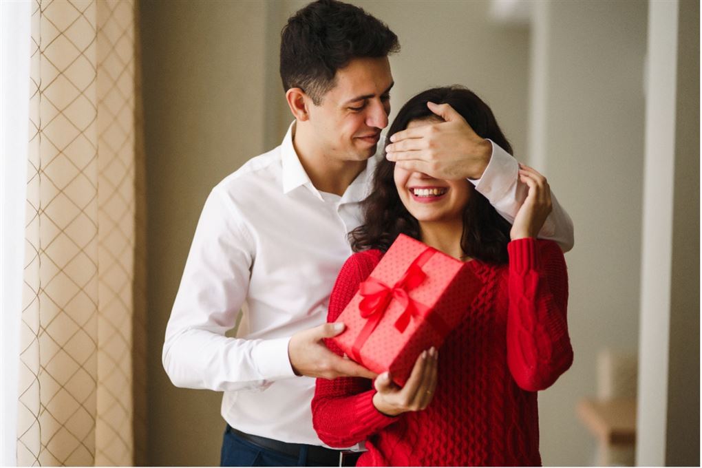 en mand overrasker en kvinde med en gave