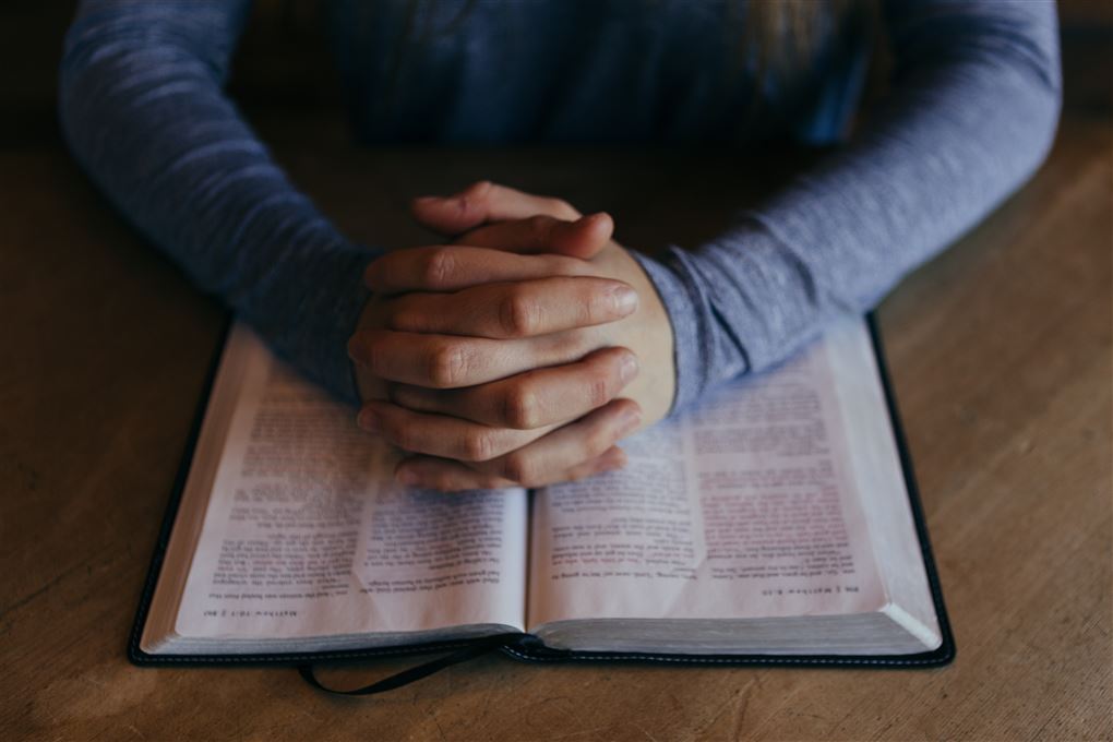 En foldet hånd over en bibel