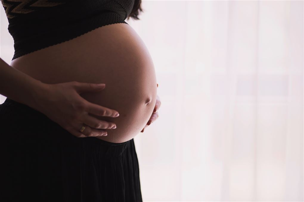 En kvinde holder på en gravid mave