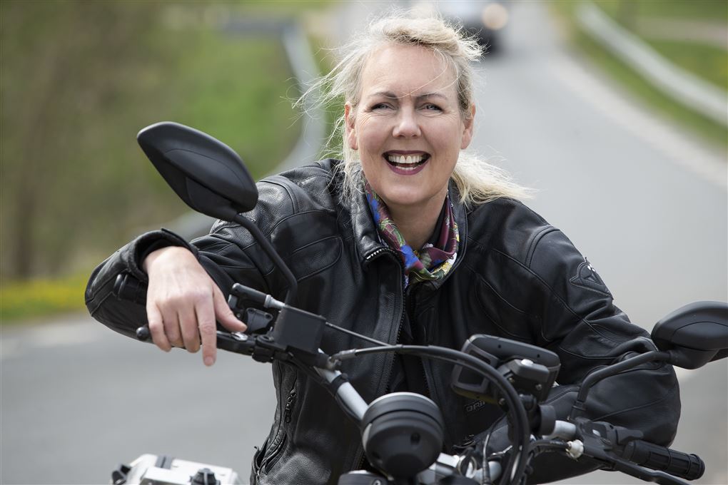 en smilende kvinde på motorcykel