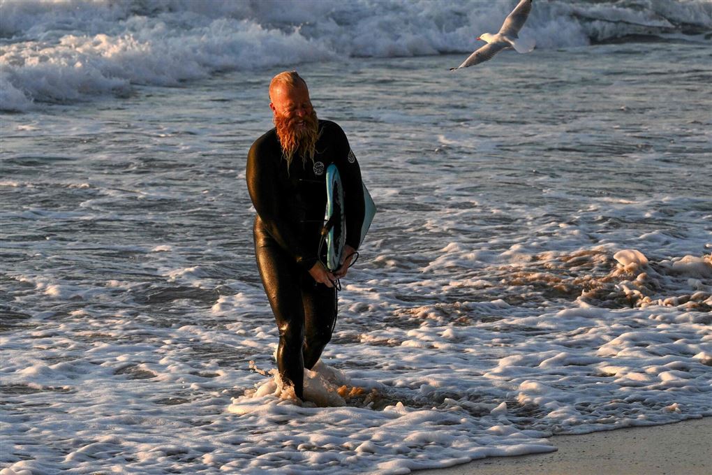 mand går i vand med surfbræt