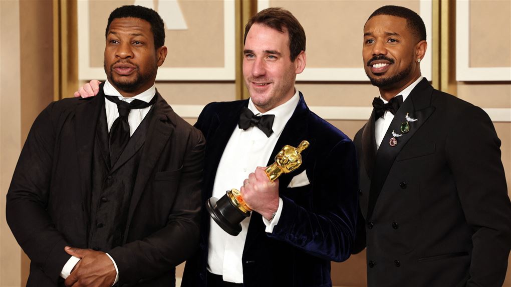 Tre mænd på scenen med en Oscar