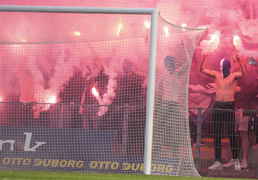En gruppe maskerede fans indhyllet i romerlys og røg