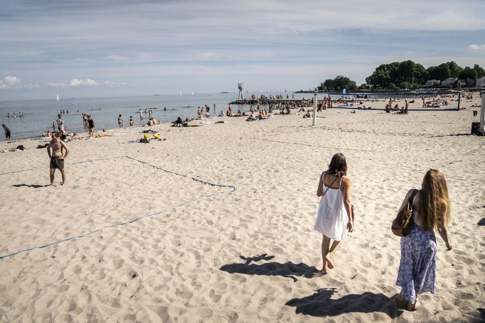 Solbeskinnet strand med sommeklædte mennesker på