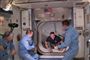 En astronaut kravler igennem slusen på Rumstationen ISS og bliver modtaget af tre andre astronauter