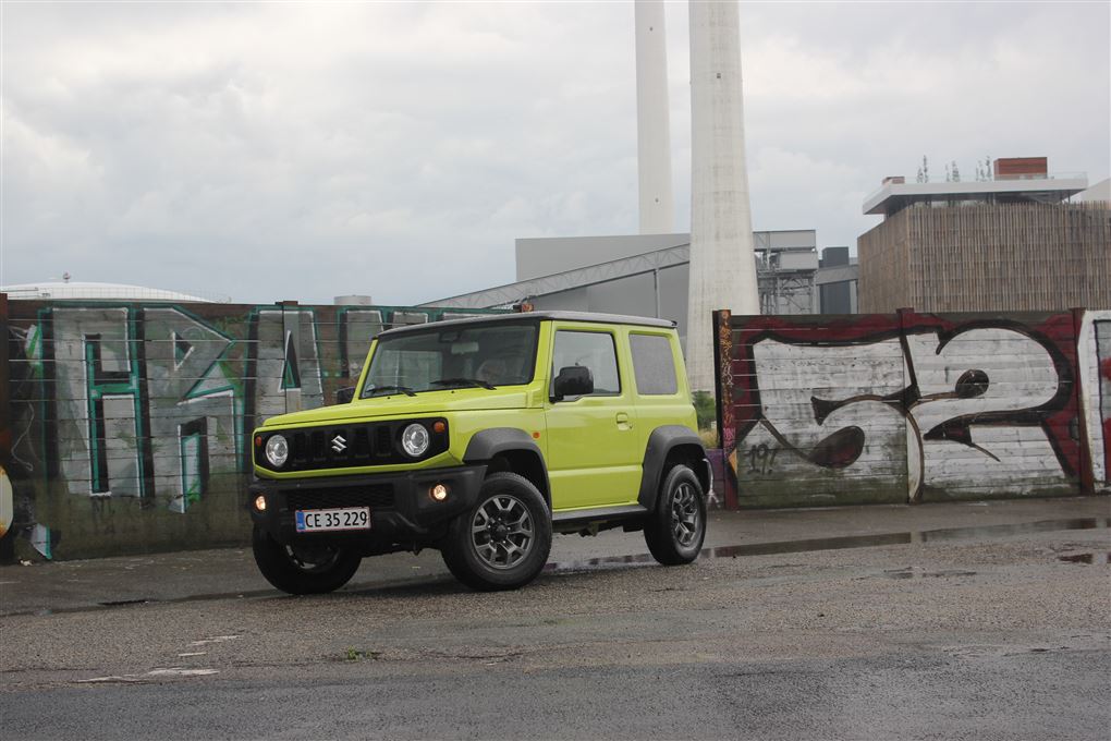 En grøn Suzuki foran grafittimur