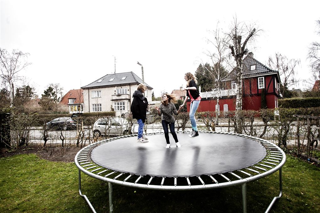 tre børn hopper på en trampolin i haven 