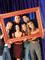 De seks skuespillere, som udgør "Friends" står bag en tom ramme og smiler.