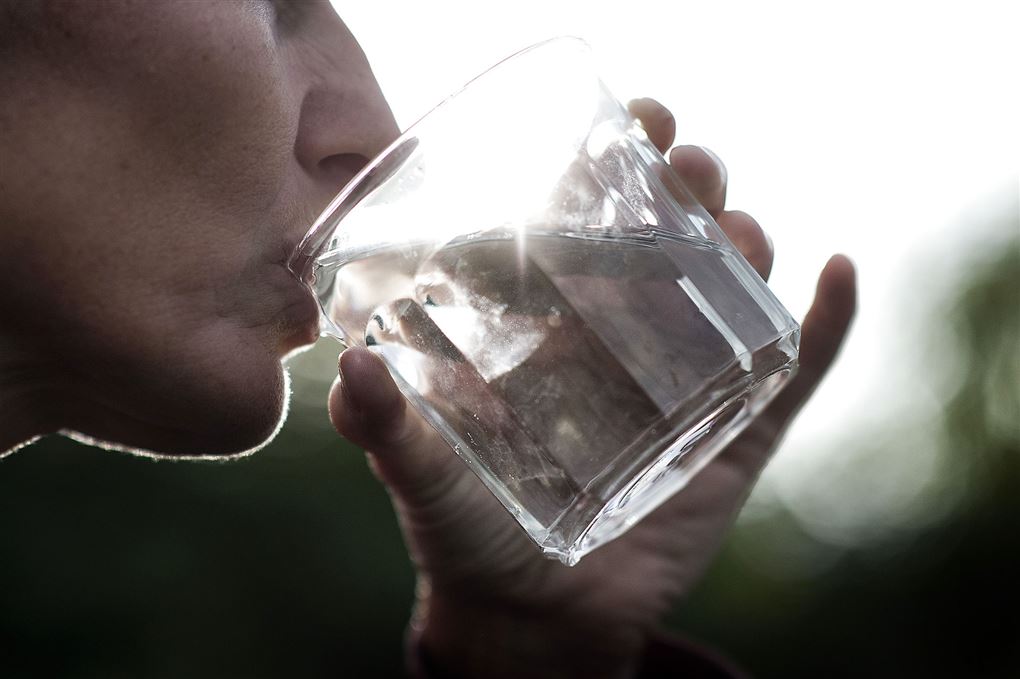 person drikker vand af et glas