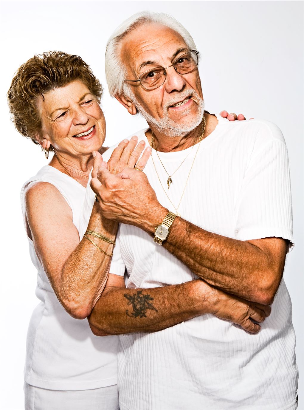 Et ældre ægtepar klædt i hvidt holder om hinanden