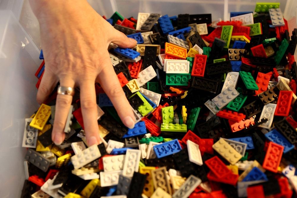 En hånd roder i en stor bunke legoklodser 