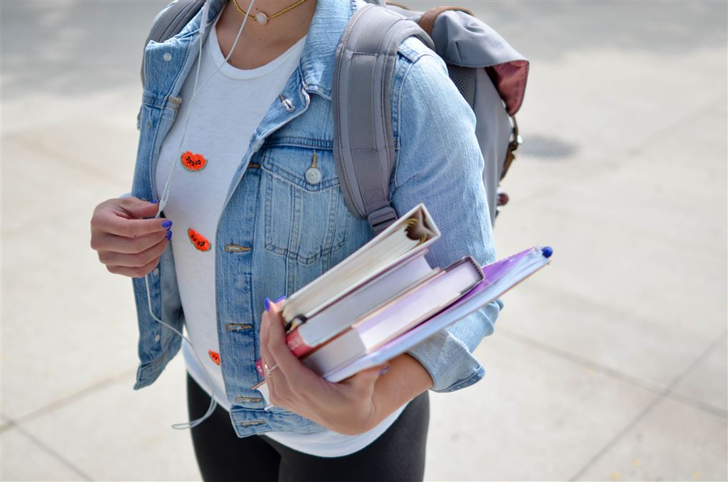 En kvindelig studerende i jeans-jakke med bøger i hånden