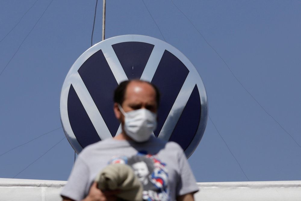 Mand med mundbind foran Volkswagen-logo.