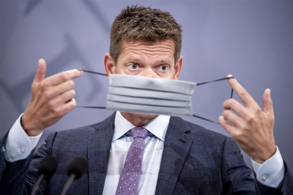 Direktør i Sundhedsstyrelsen Søren Brostrøm holder et mundbind op foran ansigtet 