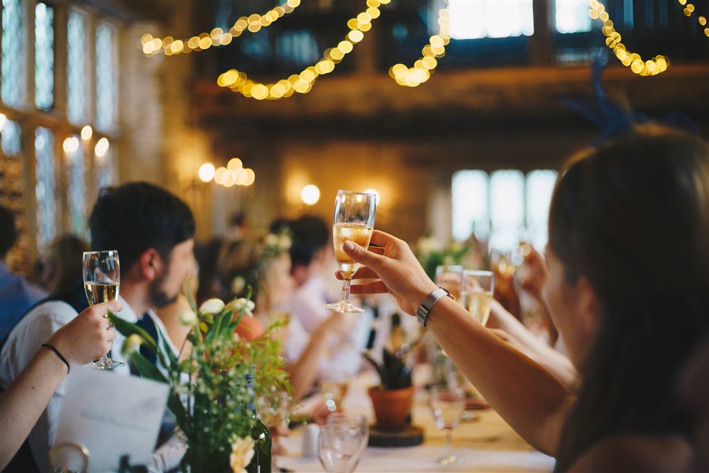 Mennesker med hævede glas ved bordet ved en festlig sammenkomst