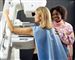 En kvinden får scannet sit bryst, mens en smilende sygeplejerske ser til