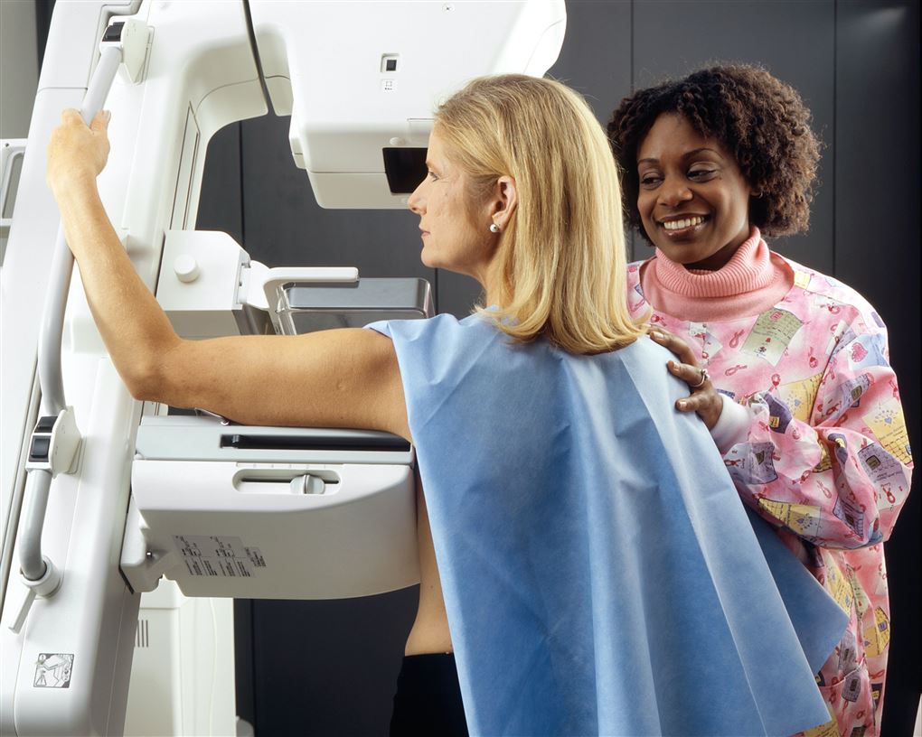 En kvinden får scannet sit bryst, mens en smilende sygeplejerske ser til