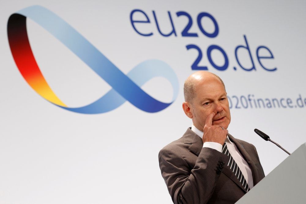 Tysklands finansminister, Olaf Scholz på en talerstol med et 20.de skilt bag sig