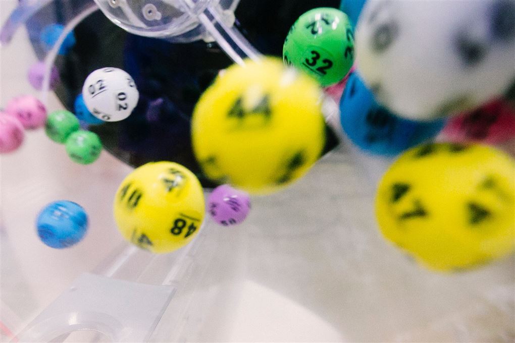 Farvede lottokugler i færd med at blive udtrukket med tallene 44 og 47 mens de andre tal er lidt slørede.