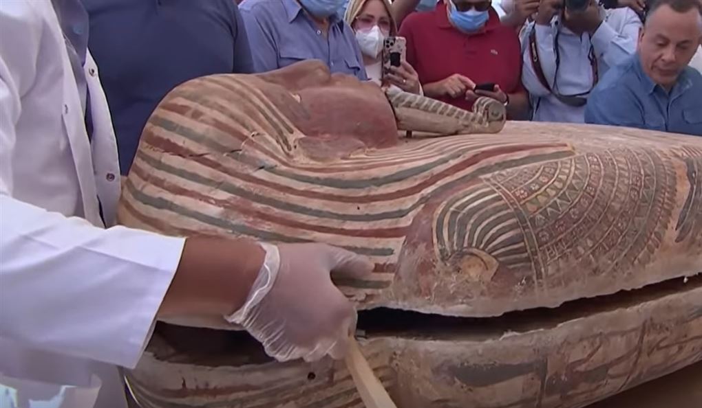 Mand løfter låg af mumiekiste i Egypten